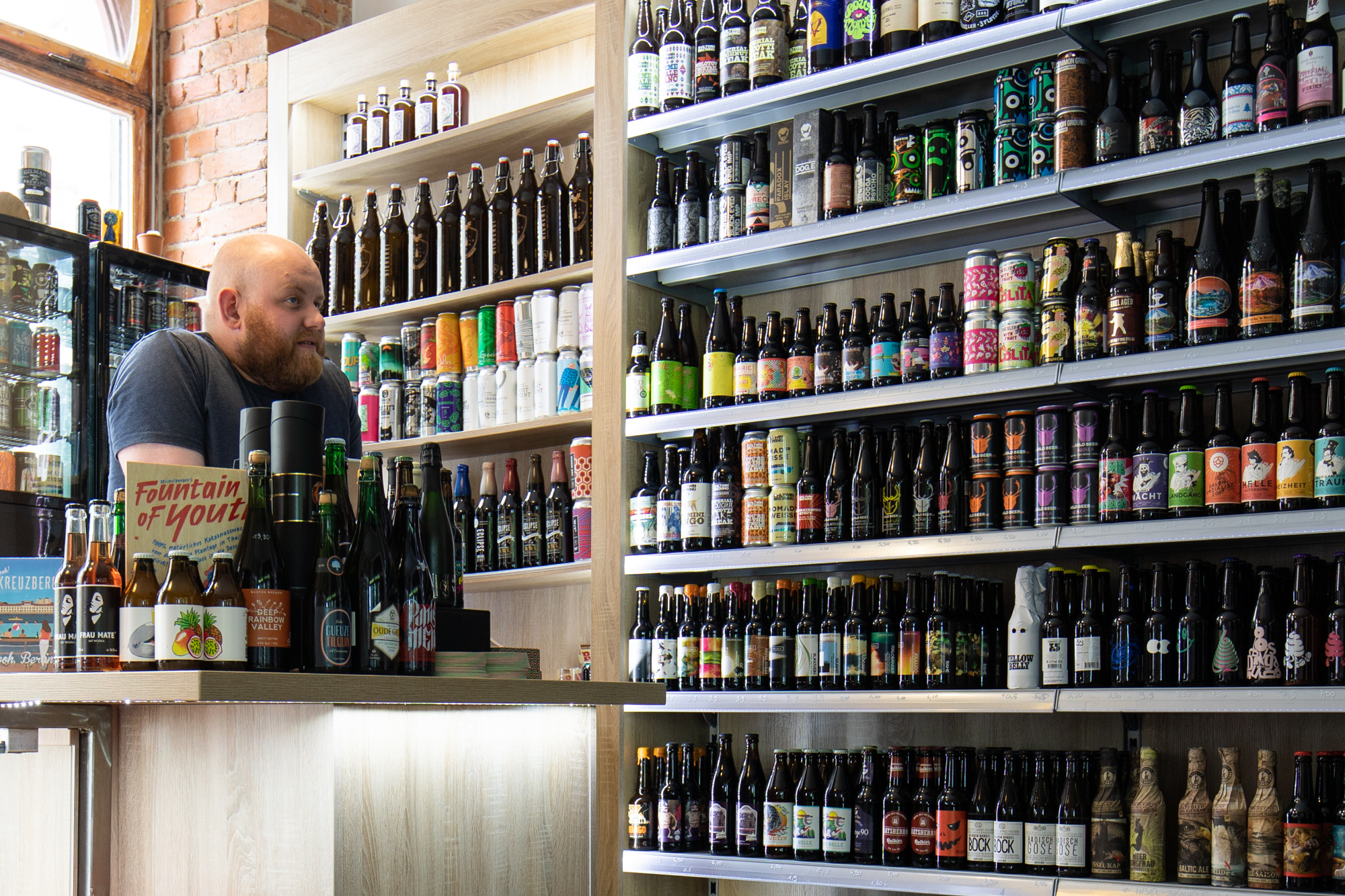 Martin giving advice to a customer scouring the shelves at Biererei Store Berlin - a craft beer bottle shop in Kreuzberg