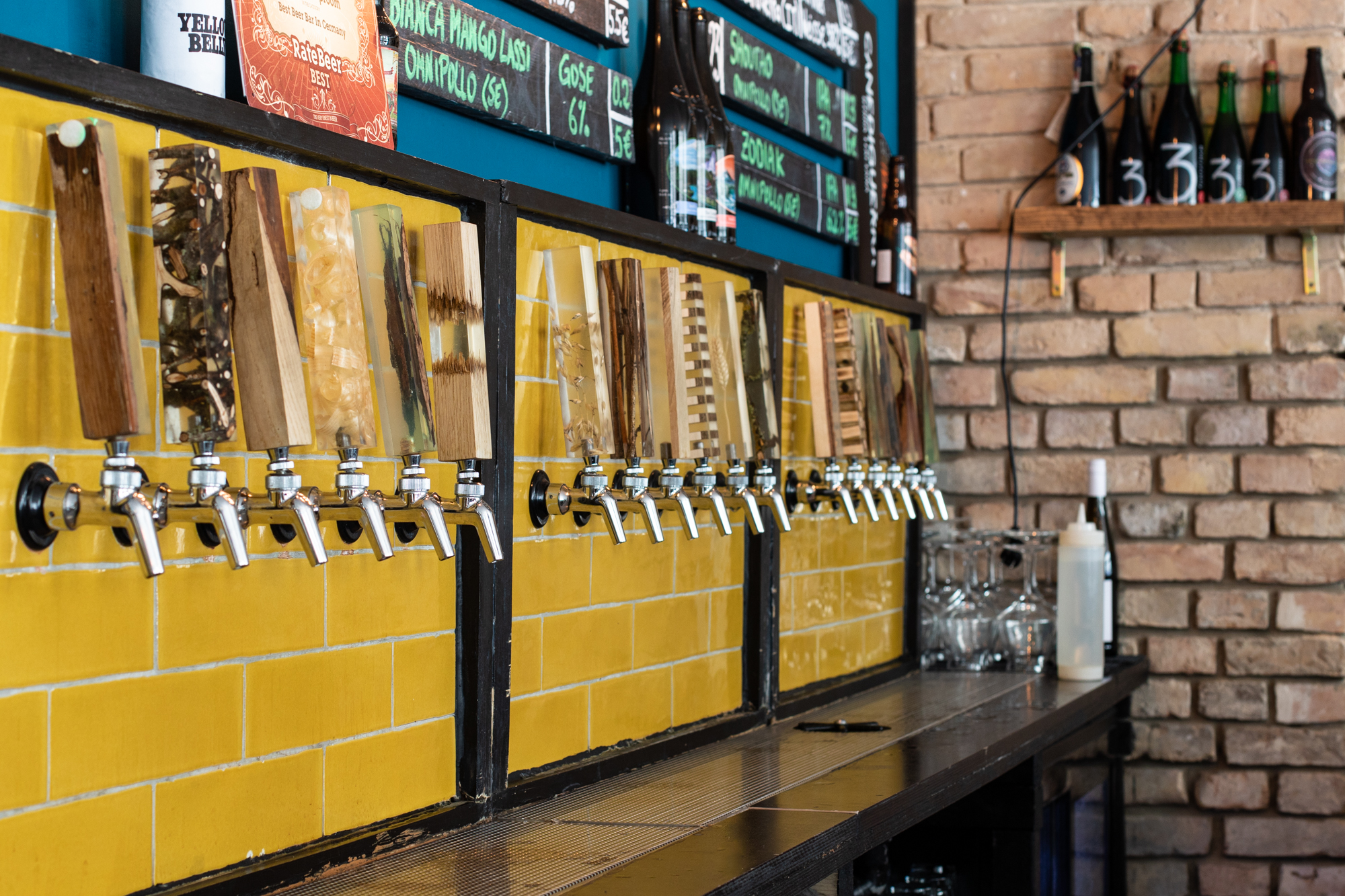 The taps and distinctive yellow tiles at Protokoll Taproom Berlin, a craft beer bar with 24 taps in Berlin Friedrichshain